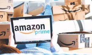 logo de amazon prime en la pantalla del portátil de una persona sentada sobre una pila de cajas de amazon