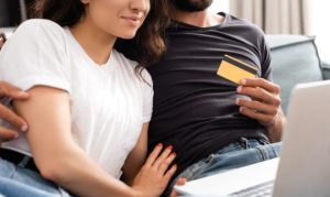 Una pareja sentada en su sofá y comprando online desde una laptop, aprovechando la llegada de Aplazo Week a México.