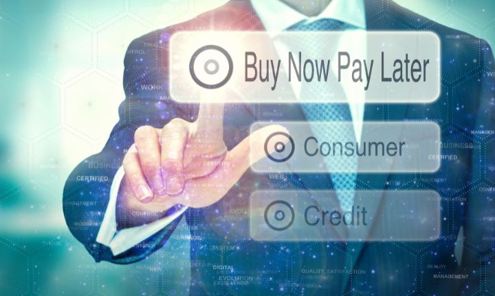 Plano medio corto de un hombre en traje interactuando con un panel digital, dando click a la opción en la que se lee "Buy Now Pay Later" (BNPL).