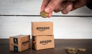 Mano sosteniendo una moneda encima de cajas de Amazon representando cómo funciona Amazon Business