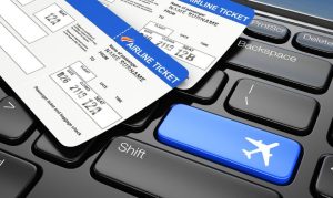 Boletos de avión físicos sobre un teclado de computadora, que tiene un botón azul con un avión mostrando la importania de las plataformas para viajes corporativos