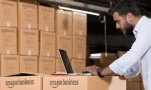 Hombre utilizando una laptop y con cajas de Amazon Business alrededor mostrando su uso en México.