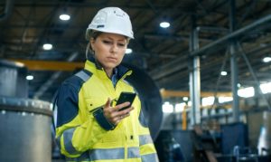 Una obrera con casco y vestimenta de trabajo navegando desde su app DataScope para tomar decisiones estratégicas.