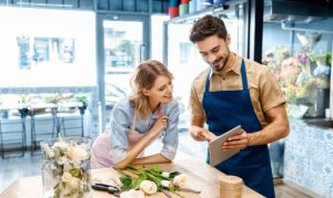 Una pareja de emprendedores en pleno proceso de digitalizar su negocio de florería, mientras observan su información en una tablet.