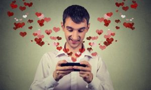 Plano medio corto de un hombre buscando desde Google en su celular cómo festejar San Valentín. Del dispositivo emanan unos íconos de corazón en referencia a la festividad.