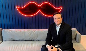 Iván Cadavid, nuevo CEO de Rappi en México, sentado en un sofá y al fondo una luz neón del isotipo de la compañía.