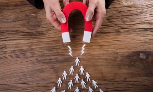 Imagen de un imán atrayendo clientes (de papel) para ilustrar el artículo sobre consejos para hacer una estrategia de lead nurturing correcta