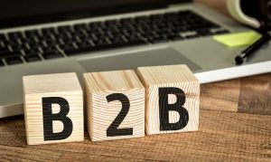 Bloques de madera en los que se lee B2B, y en el fondo una laptop.