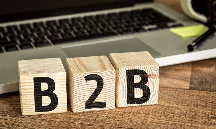Bloques de madera en los que se lee B2B, y en el fondo una laptop.