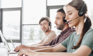 Equipo de ventas haciendo marketing telefónico, cada uno de ellos portando una diadema de comunicación y frente a sus computadoras.