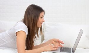 Una usuaria recargada en su cama y comprando online desde su laptop; esto en referencia a lo hábitos de compra de los mexicanos en Mercado Libre.