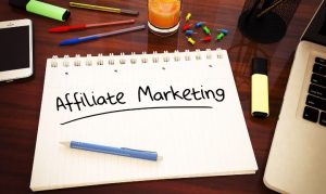 Toma picada de una libreta en la que se lee "affiliate marketing", acompañada de una laptop y plumones.