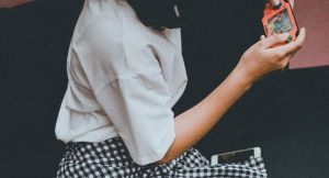 Mujer joven de lado sentada en un sofá negro, utilizando un dispositivo móvil con lo que se representa el mobile gaming en México