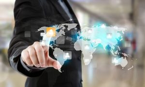 Un hombre de negocios tocando una pantalla virtual, en la que se despliegan los continentes y vemos reflejado el proceso de nearshoring en México y el mundo.