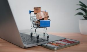 Un carrito de compras con productos encima de una laptop; esto en referencia a los retos y desafíos del eCommerce en México.