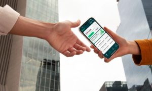 Dos manos extendidas intercambiando un celular, donde se percibe la app de Stori y su nueva solución de inversión.