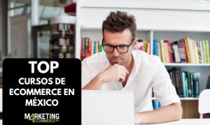 Un hombre con lentes tomando cursos de eCommerce desde su laptop. Lo encontramos en una biblioteca y portando unos lentes.