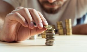 Hombre apilando monedas y haciendo uso de efectivo en México.