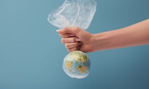 Una figura de un mundo siendo envuelta por una bolsa de plástico, en referencia al uso excesivo de plásticos en eCommerce.