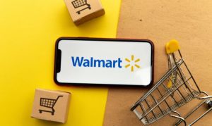Plano cenital de un celular con la identidad gráfica de Walmart sobrepuesto en un fondo mitad amarillo mitad café; en referencia a la inversión de Walmart a su eCommerce en México.